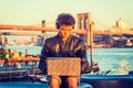 Young Asian American college student working on laptop computer outddors by river in New York City Royalty Free Stock Photo