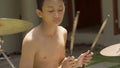 Asian American teenager playing drums. Summer portrait of handsome young boy practicing on drum kit at home garden rehearsing rock Royalty Free Stock Photo