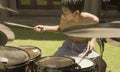 Asian American teenager playing drums. Summer portrait of handsome young boy practicing on drum kit at home garden rehearsing rock Royalty Free Stock Photo