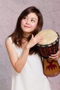 Asian American woman playing African hand drum Royalty Free Stock Photo