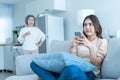 Asian angry senior mature woman shouting at stubborn fussy daughter. Young female sit on sofa use mobile phone chat, disobedient Royalty Free Stock Photo