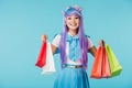 Asian anime girl holding shopping bags isolated on blue