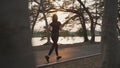 Asian athlete woman in black sportswear and wireless headphone running in urban city trees park during sunset and bad cloudy Royalty Free Stock Photo