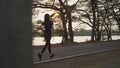 Asian athlete woman in black sportswear and wireless headphone running in urban city trees park during sunset and bad cloudy Royalty Free Stock Photo