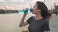 Asian athlete woman in green nature tree park and lake in evening sunset feeling thirsty drink water from bottle. energy drinks