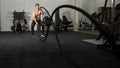 Asian athletic man with rope doing exercise in fitness gym