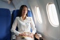 Asian attractive business woman passenger sitting on business class luxury plane while relax while travel concept Royalty Free Stock Photo