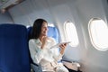 Asian attractive business woman passenger sitting on business class luxury plane while tablet computer while travel