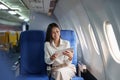 Asian attractive business woman passenger sitting on business class luxury plane while tablet computer while travel