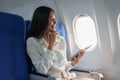 Asian attractive business woman passenger sitting on business class luxury plane while tablet computer while travel