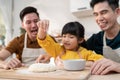 Asian attractive LGBTQ gay family teach girl kid making yeast dough. Handsome male couple take care and spend time with little