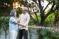 Asian attractive senior couple spending time outdoor gardening together at home. Old grandparents use hose to watering Plants in Royalty Free Stock Photo