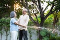 Asian attractive senior couple spending time outdoor gardening together at home. Old grandparents use hose to watering Plants in t Royalty Free Stock Photo