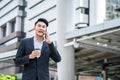 Asian attractive smart Businessman walk outdoor in city, talk to colleagues on mobile phone about office company. Handsome male in Royalty Free Stock Photo