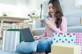 Asian attractive woman enjoy shopping online in living room at home. Beautiful girl sit on floor, hold credit card to make e-bank Royalty Free Stock Photo