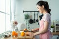 Asian attractive woman make drinking orange juice in kitchen at home. Smiling young beautiful girl wear apron feel happy enjoy Royalty Free Stock Photo