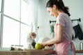 Asian attractive woman make drinking orange juice in kitchen at home. Smiling young beautiful girl wear apron feel happy enjoy Royalty Free Stock Photo