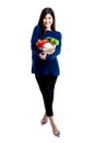 Asian attractive woman, standing and holding a bowl containing fresh fruit and vegetables Royalty Free Stock Photo