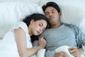 Asian attractive young couple lying down on bed to sleep in bedroom. Beautiful new marriage man and woman in pajamas feel happy