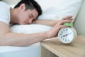 Asian attractive young man turn off alarm clock ringing in the morning. Handsome male feel lazy and tired lying down on Royalty Free Stock Photo