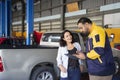 asian auto mechanic man holding clipboard paper and explain details of the car maintenance and repair to the owner Royalty Free Stock Photo