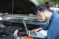 Asian auto mechanic testing car ECU with laptop