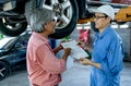 Asian automotive technician discuss about contact form to senior customer during service to fix problem for his car in workplace