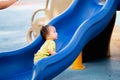 Asian baby boy climbs the children's slide on playground. Child playing happily in summer or spring times. Royalty Free Stock Photo