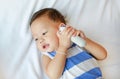 Asian baby boy with holding ear thermometer on bed at home Royalty Free Stock Photo