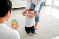 Asian baby boy toddler taking first steps. Family of father and mother encouraging their son learning to walk