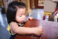 Asian baby child girl is using a hand to hold a banknote to put in a box to donate or make merit in accordance with Buddhist.