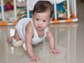 Asian baby crawling on floor in her house.