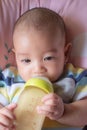Asian baby drinking milk from bottle Royalty Free Stock Photo