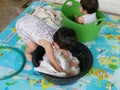 Asian baby girl left soaking clothes in water to wash it at home