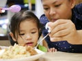 Asian baby girl looking at a spoon scooping rice by her mom to feed her Royalty Free Stock Photo