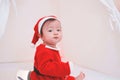 Asian baby girl in a Santa costume. Beautiful little baby celebrates Christmas. Christmas baby.