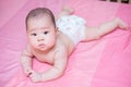 Asian baby girl scowl on pink bed Royalty Free Stock Photo