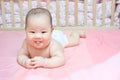 Asian baby girl scowl on pink bed Royalty Free Stock Photo