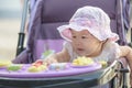 Asian baby girl sitting and playing in stroller on a walk.