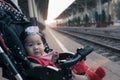 Asian baby girl sitting in stroller in railway station.