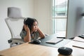 Asian baby girl wearing headphone to listen music or using white keyboard laptop and study online on wood table desk in living Royalty Free Stock Photo