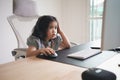 Asian baby girl wearing headphone to listen music or using white keyboard laptop and study online on wood table desk in living Royalty Free Stock Photo