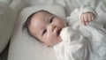 Asian baby infant laying down on white soft bed sucking hand and fingers. 3 months old baby facial expression. sign and symptom of Royalty Free Stock Photo