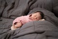 Asian baby infant wearing gloves and socks sleeping on gray bed. studio shot.