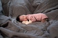 Asian baby infant wearing gloves and socks sleeping on gray bed. studio shot.
