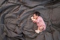 Asian baby infant wearing gloves and socks sleeping on gray bed. studio shot.