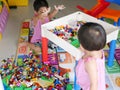 Asian baby left is cleaning up toys she played with her little sister