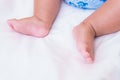 Asian baby`s feet are sleeping on a white bed sheet with copy space Royalty Free Stock Photo