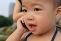 Asian baby in sling suit,murmuring to a cellphone