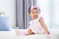 Asian baby toddler in cute pink dress is smiling while sitting on bed with happiness for healthy kid and adorable girl portrait Royalty Free Stock Photo